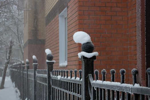 A snow cap on a wrought iron fence after a cold winter blizzard.