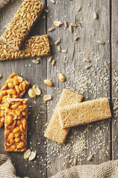 Mix of Gozinaki bar of seeds on a vintage background with burlap. Delicious oriental sweets from the seeds of sunflower, sesame and peanuts, covered with honey with shiny glaze. Macro Country Style vertical frame