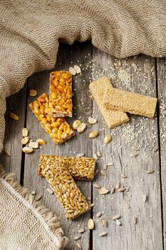 Assorted kozinaki, on old vintage background, with burlap fabric. Country style. Delicious sweets from the seeds of sunflower, sesame and peanuts, covered with shiny glaze. View from above