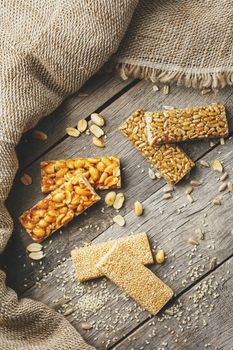Mix of Gozinaki bar of seeds on a vintage background with burlap. Delicious oriental sweets from the seeds of sunflower, sesame and peanuts, covered with honey with shiny glaze. Macro Country Style vertical frame