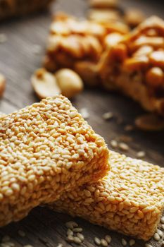 Assorted kozinaki, on old vintage background, with burlap fabric. Country style. Delicious sweets from the seeds of sunflower, sesame and peanuts, covered with shiny glaze. Macro, close-up