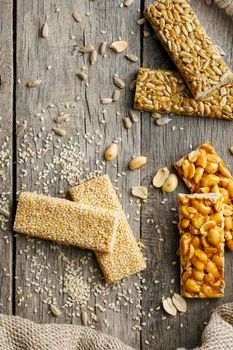 Assorted kozinaki, on old vintage background, with burlap fabric. Country style. Delicious sweets from the seeds of sunflower, sesame and peanuts, covered with shiny glaze. View from above. Vertical