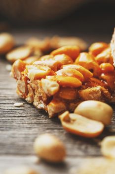 Sweets bar of peanuts on a vintage background with burlap. Delicious oriental sweets Gozinaki from sunflower seeds, sesame and peanuts, covered with honey with a shiny icing. Country style. Macro, vertical frame