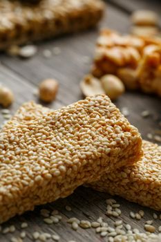 Sesame seed casinos on old vintage background with burlap cloth. Country style. Delicious sweets from seeds of sunflower, sesame and peanuts, covered with shiny glaze. Macro, macro, vertically