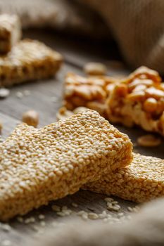 Sesame seed casinos on old vintage background with burlap cloth. Country style. Delicious sweets from seeds of sunflower, sesame and peanuts, covered with shiny glaze. Macro, macro, vertically