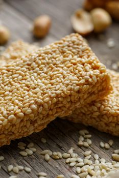 Sesame seed casinos on old vintage background with burlap cloth. Country style. Delicious sweets from seeds of sunflower, sesame and peanuts, covered with shiny glaze. Macro, macro, vertically