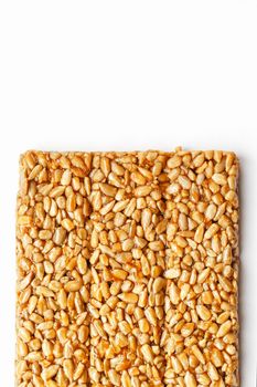 A large golden tile of sunflower seeds, a bar in a sweet molasses on a white background. Kozinaki useful and tasty sweets of the East. Top view, isolated.