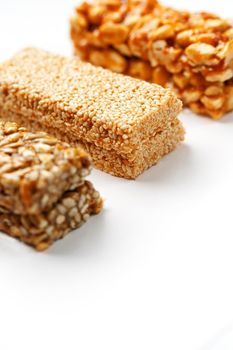 Grain granola bar with peanuts, sesame and seeds in a row on a white background. Top view Kozinaki Three assorted bars, isolate