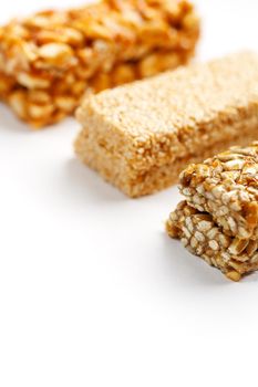 Grain granola bar with peanuts, sesame and seeds in a row on a white background. Top view Kozinaki Three assorted bars, isolate