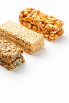 Grain granola bar with peanuts, sesame and seeds in a row on a white background. Top view Kozinaki Three assorted bars, isolate
