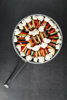 Ratatouille dish of fresh vegetables in a frying pan on a dark background. Traditional French vegetarian dish