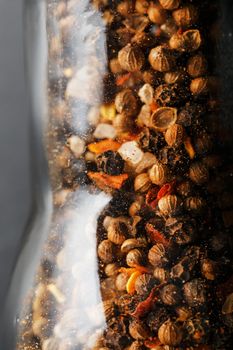 A mixture of seasonings, spices and herbs in a glass mill on a black background. Free space top view, minimalism