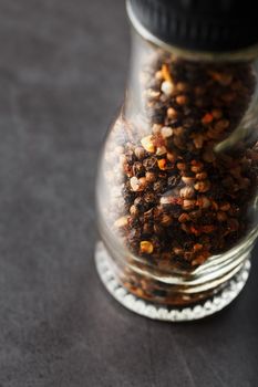 A mixture of peppercorns seasoning and salt in a transparent mill close-up. Macro
