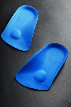 Orthopedic insoles for correction of the blue color of the foot on a black background. Free space