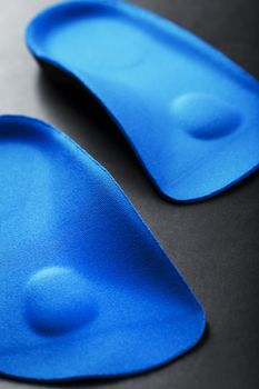 Orthopedic insoles for correction of the blue color of the foot on a black background. Free space