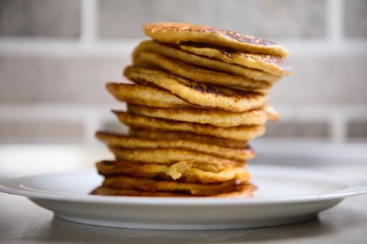 Close-up of a stack of freshly baked pancakes on a white ceramic plate. Shrove Tuesday concept