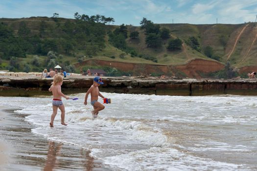 Two little boys are playing on the seashore. Children playing on the beach