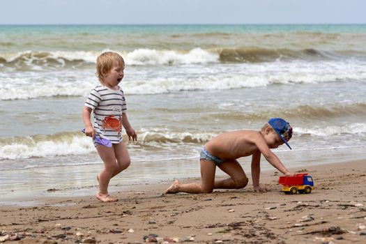 Two little boys are playing on the seashore. Children playing on the beach