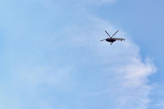 Flying helicopter against the background of a blue sky with spruce clouds. Blank for designers