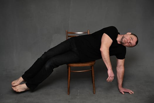 a man lies on a chair looking up on a gray background