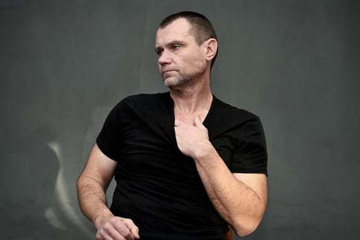 Portrait of an adult calm man looking away on a gray background