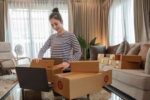 Young asian woman entrepreneur, teenager is work at home business owner by computer in morning. Happy woman is smilling for her work. SME work at home concept.