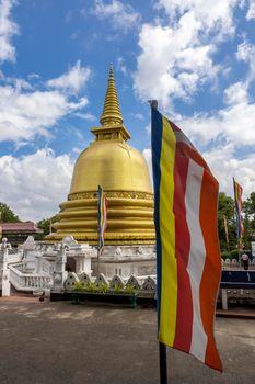 Sri Lanka. The golden Temple of Dambulla. View of the golden stupa on the background of the flag and the blue sky. High quality photo