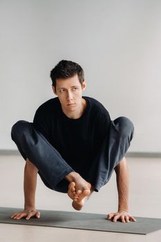 A man in a black T-shirt trains lying down doing stretches in the gym.