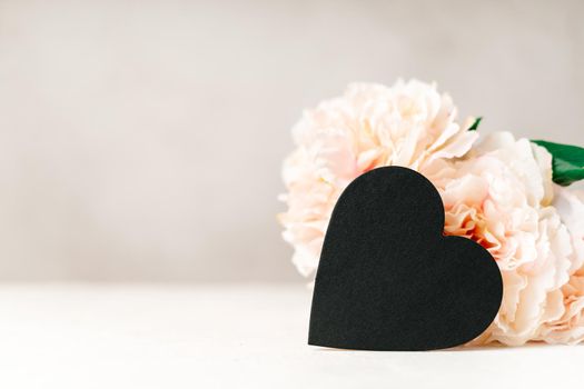 Still life Valentines day festive background with empty black chalkboard heart on white table background. Mockup with copy space for design.