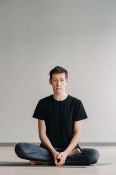 A male athlete in a black T-shirt is sitting in the gym before training and resting.