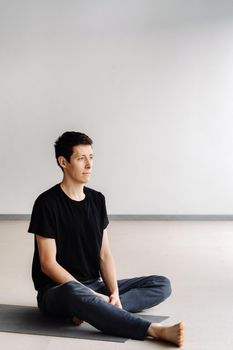 A male athlete in a black T-shirt is sitting in the gym before training and resting.