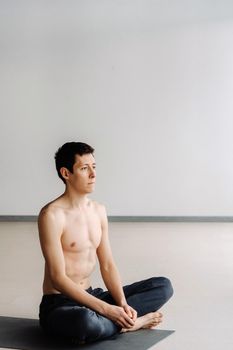 A male athlete with a bare torso is sitting in the gym before training and resting.