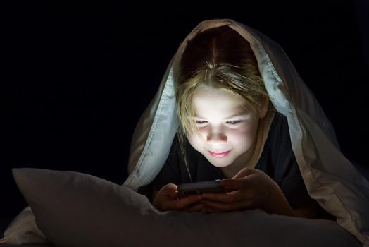 Gadget night. Romantic chat. Late home leisure. Online communication. Portrait of girl with mobile phone under blanket at night. cyber bullying