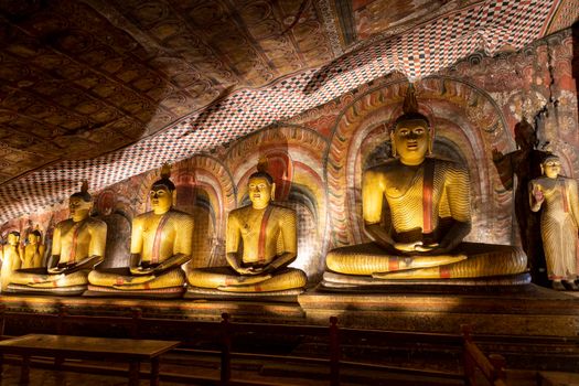 Sri Lanka. Dambulla Cave Temple. Buddha statues sitting in a row, illuminated by lamps from below. High quality photo