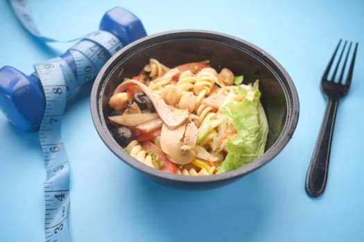 Fresh homemade salad in a plate with dumbbell on table .