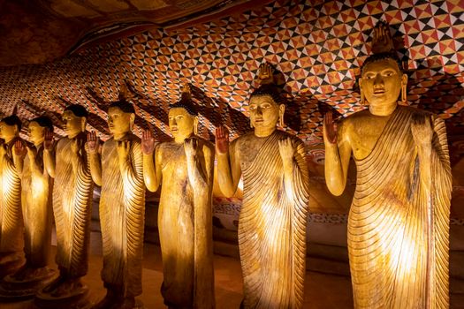 Sri Lanka. Dambulla Cave Temple. Buddha statues standing in a row, illuminated by lamps from below. High quality photo