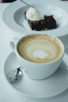 a cup of late coffee with flower shape design on top at cafe .