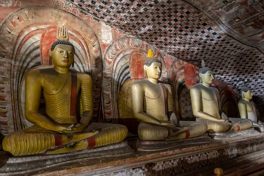 Sri Lanka. Dambulla Cave Temple. Buddha statues sitting in a row, illuminated by lamps from below. High quality photo