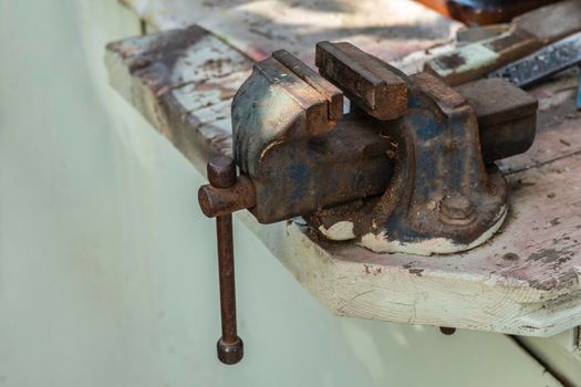 Old vise on a wooden workbench in a rustic workshop