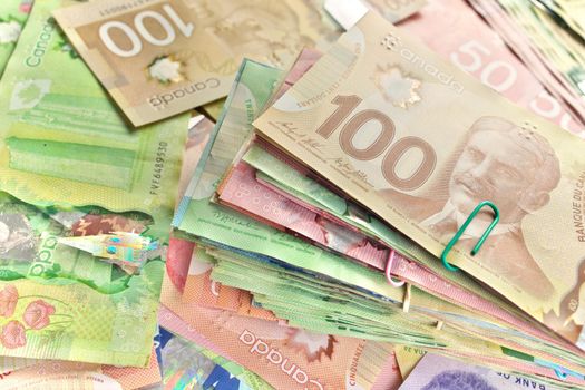 A High Angle View of Canadian Banknotes of Different Values. Banknotes are piled randomly on top of each other and have values of 5 five, 10 ten, 20 twenty, 50 fifty, and 100 one hundred dollars. Full Frame High quality photo