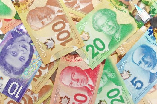 A Directly Above Full Frame Image of Canadian Banknotes of Different Values. Banknotes are piled randomly on top of each other and have values of 5 five, 10 ten, 20 twenty, 50 fifty, and 100 one hundred dollars. High quality photo