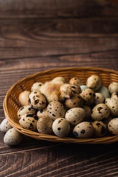 Quail chicken and quail eggs in a straw basket on a wooden background