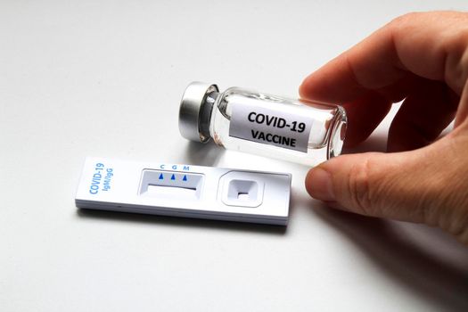 Rapid Antigen Diagnostic Test cassette of Coronavirus SARS-CoV-2 Covid-19 and vial with vaccine on white background
