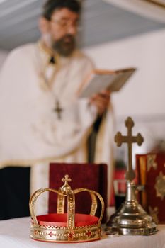 Gold crown and cross stand on the table in the church in front of the priest. High quality photo