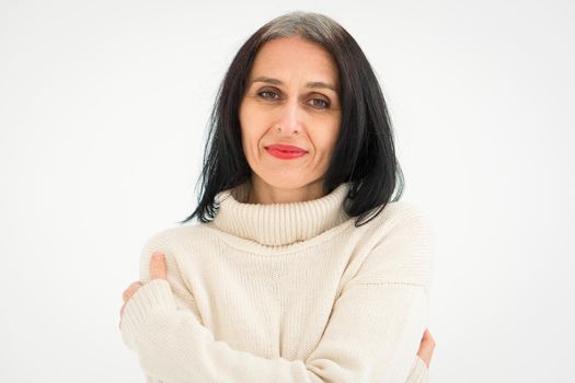 Middle aged woman starting getting grey-haired is posing in studio in sweater on white background, face skin care beauty, middle age skincare cosmetics, cosmetology concept.