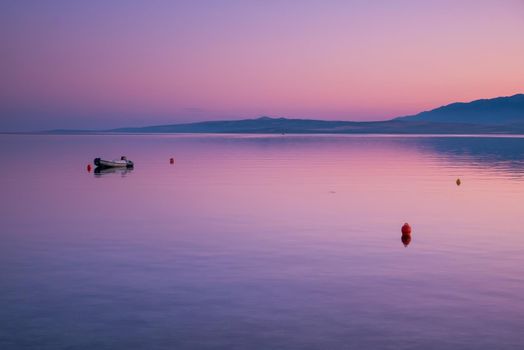 Sea view on island Vir, Croatia early in the morning. Sea buoys and rubber boat overlooking beautiful purple and pink sky over Adriatic sea.