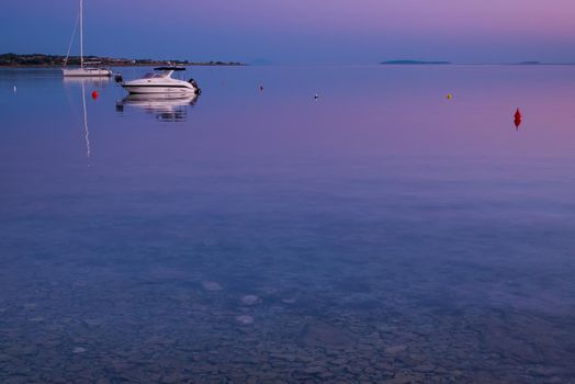 Sea view on island Vir, Croatia early in the morning. Two white boats overlooking beautiful purple and pink sky over Adriatic sea.