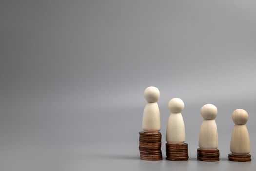 Miniature people standing on piles of different heights of coins. The concepts of person and wealth. investment and teamwork growth copy space