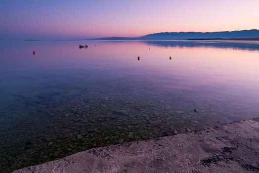 Dock, quay on island Vir, Croatia early in the morning. Dock and rubber boat overlooking beautiful purple and pink sky over Adriatic sea.