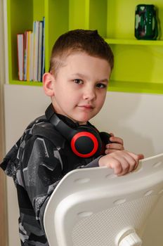 A little boy listens to music in wireless headphones at home, close-up.